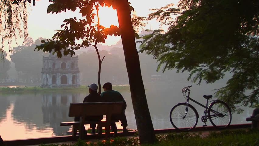People sit in a park in Hanoi at sunset and admire the view