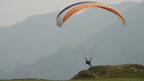 NEPAL, POKHARA - 15 APRIL 2016: Young paraglider pilot repelled from slope and takes off