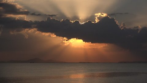 Sunset over the ocean with sunrays coming out from behind a big black cloud. Filmed in 4k outside Pattaya.