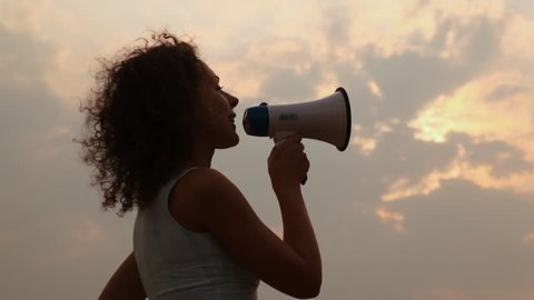 woman stands and tells something in megaphone lifts it upwards