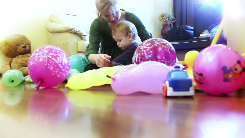 Mother and baby boy playing, surrounded by toys