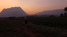 Aerial shooting from drone of young woman wanderer is making photo with mobile phone camera of a beautiful sunset scenery in summer evening. Female traveler taking picture with cellphone during travel