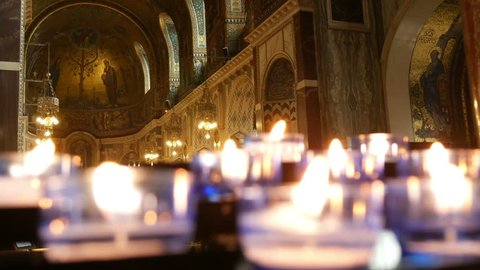 Votive candles in a catholic cathedral.
Foreground of votive candles. Background is in focus and is a golden mosaic.