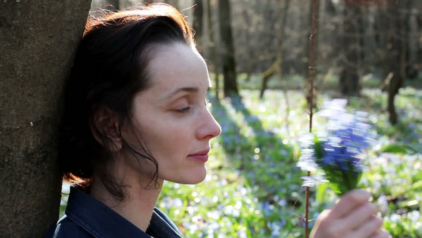 The young woman smelling the bouquet of the bluebells