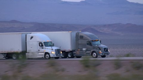 4K CLOSE UP: Freight semi truck driving and transporting cargo container on busy highway, delivering goods. Trucks speeding and overtaking