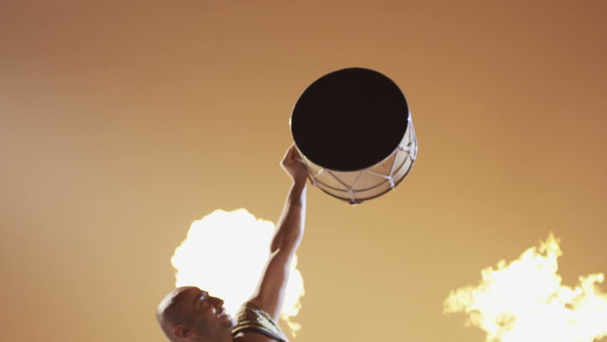 Shaman dancing and playing drum on grey background.  Ethnic Asian Dancer on Fire background. Shot on RED EPIC DRAGON Cinema Camera in slow motion.
