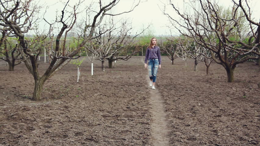 Gardening. The company of young people working in the garden. Girl goes near the trees. Series
