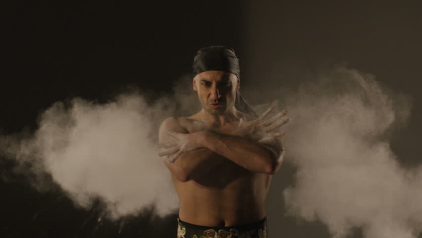 Ethnic Dance.  Man dancing with sand on grey background. Shot on RED EPIC DRAGON Cinema Camera in slow motion.