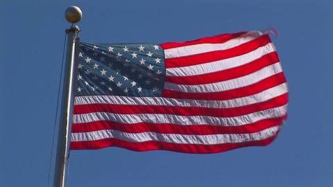 American flag fluttering in the wind against a blue sky  