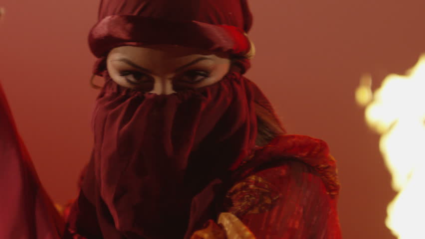 Beautiful traditional oriental belly dancer. Oriental girl dancing on red background. Studio shoot with fire.  Shot on RED EPIC DRAGON Cinema Camera in slow motion.