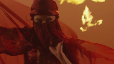 Beautiful traditional oriental belly dancer. Oriental girl dancing on red background. Studio shoot with fire.  Shot on RED EPIC DRAGON Cinema Camera in slow motion.