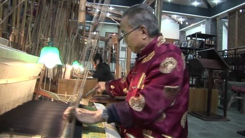 BEIJING, CHINA - CIRCA 2009: Chinese workers weave on a hand loom with great speed and accuracy, circa 2009 in Beijing.