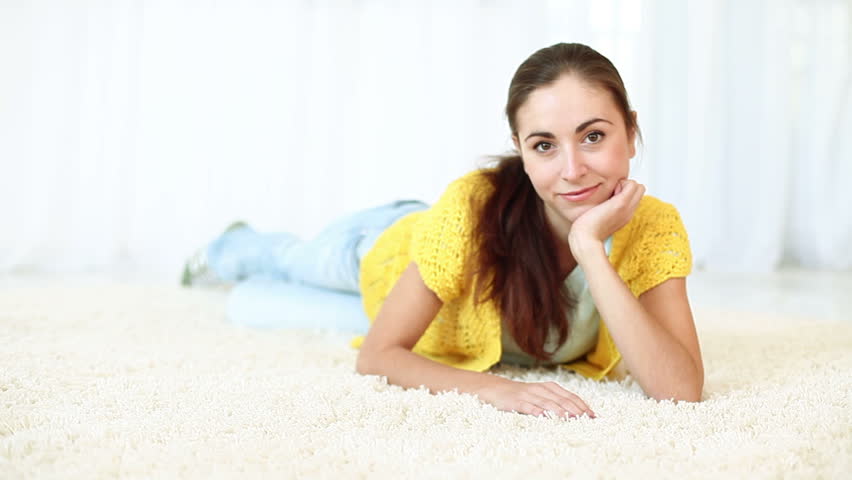 Beautiful young adult smiling while lying on the carpet. DOLLY HD