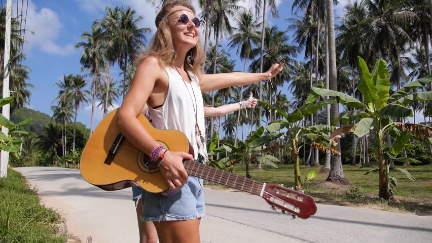 Hippie Girls Hitchhiking on Tropical Road. Slow Motion. 