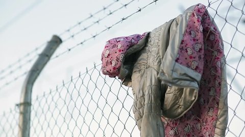 A child's jacket hangs on a razor wire fence erected to keep immigrants away.