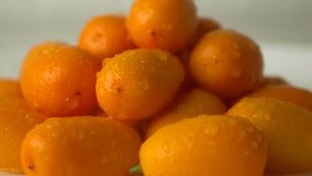 Small water drops hit heap of orange kumquat. Super slow motion video