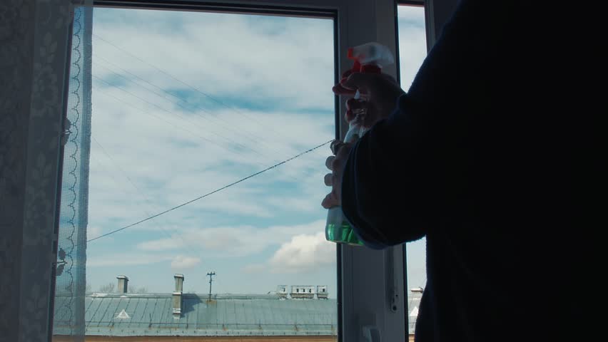The woman washes a window and listening to music on headphones . Spring mood . Bringing order . Cleaning service . Good hostess .