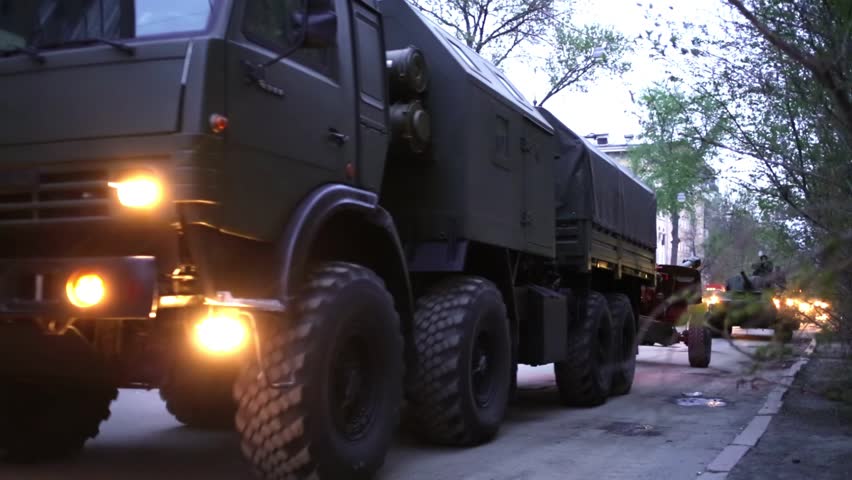 Columns of trucks with trailers guns and soldiers in armored vehicles riding through streets of Samara on military celebration.
