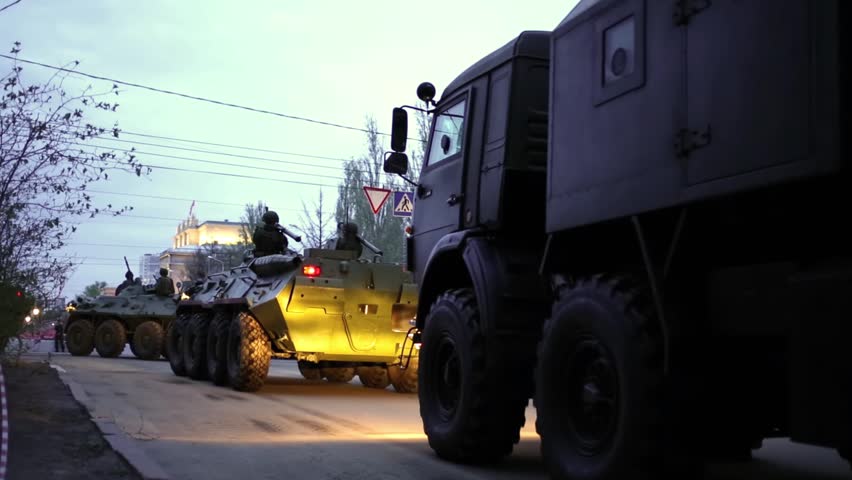 Soldiers with rocket launchers on their shoulders riding on armored vehicles and military trucks on streets of Samara on military celebration.