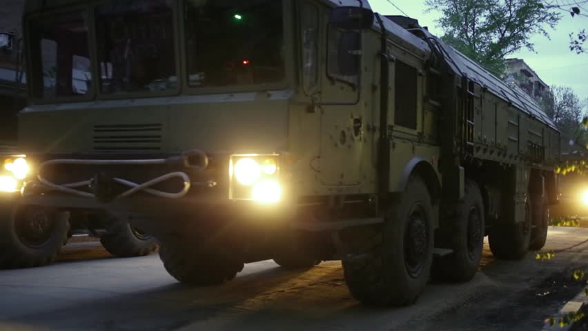 Two rows of machines Iskander - operational-tactical missile systems riding on streets of Samara at dusk on military celebration.