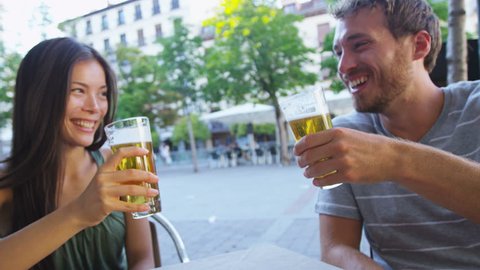 Couple eating tapas drinking beer in Madrid, Spain. Romantic man and woman enjoying local traditional food on square in Madrid. Asian woman and Caucasian man dating. Focus on beer and food.