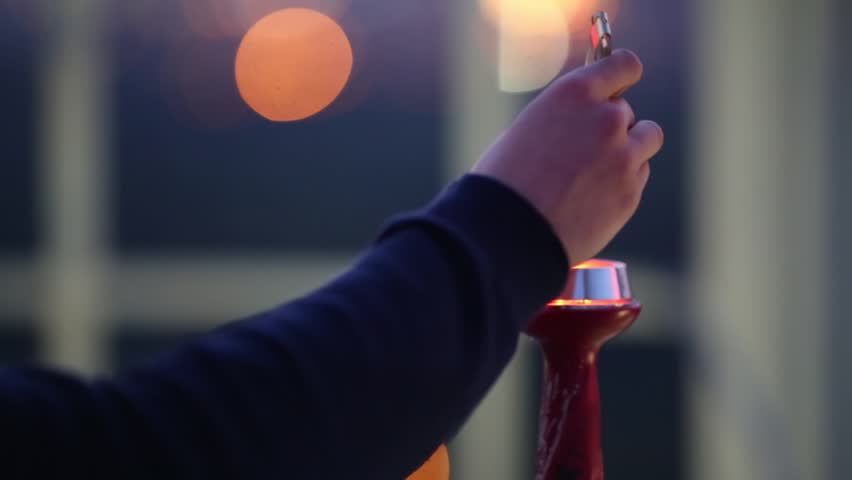 Hand with tweezers taking coal from hookah and sparks fly out close up.