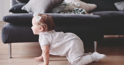 Baby is crawling at home, Slow Motion 120 fps, 4K DSi. Cute little baby girl crawling and smiling at the floor in a cozy sunlit room, baby milestone, toddler, 1 year old. Happy childhood. Cinematic Stockvideo