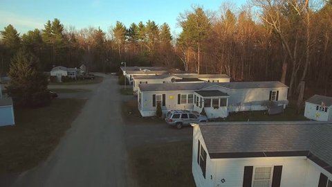 Aerial flyover view of a mobile trailer home park at sunset.