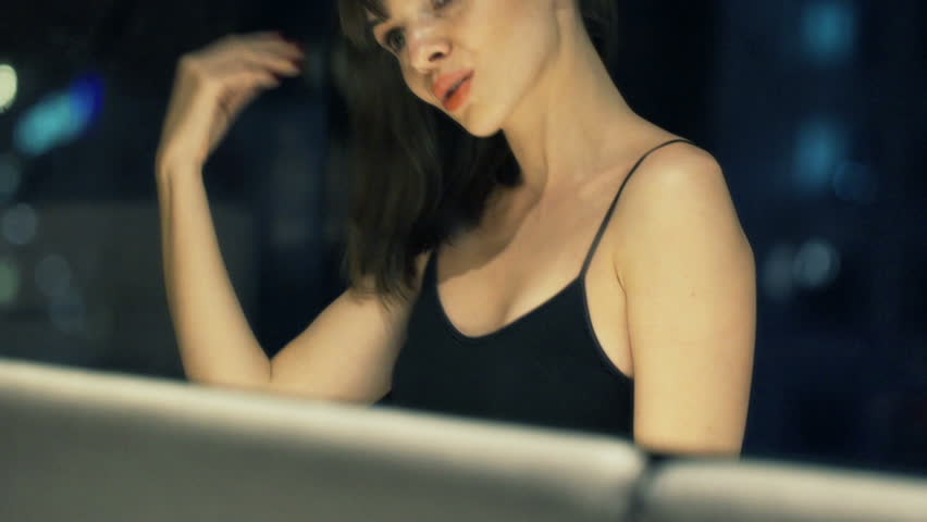 Young, pretty woman checking her appearance in mirror at night
