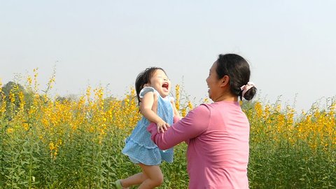 Mother and daughter spinning around in flower field,slow motion