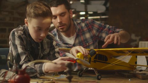 Father and son are modeling a toy airplane in a garage at home. Shot on RED Cinema Camera in 4K (UHD).