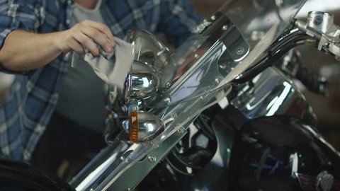 Man is cleaning and polishing chrome objects on his motorcycle in a garage. Shot on RED Cinema Camera in 4K (UHD).
