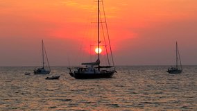beautiful natural scenic of sun set behind sailing boat and people playing surfing kite 