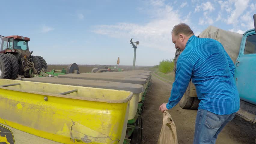 The farmer sleeps grain in a special tractor for planting wheat. Eastern Ukraine. Planting of spring wheat.