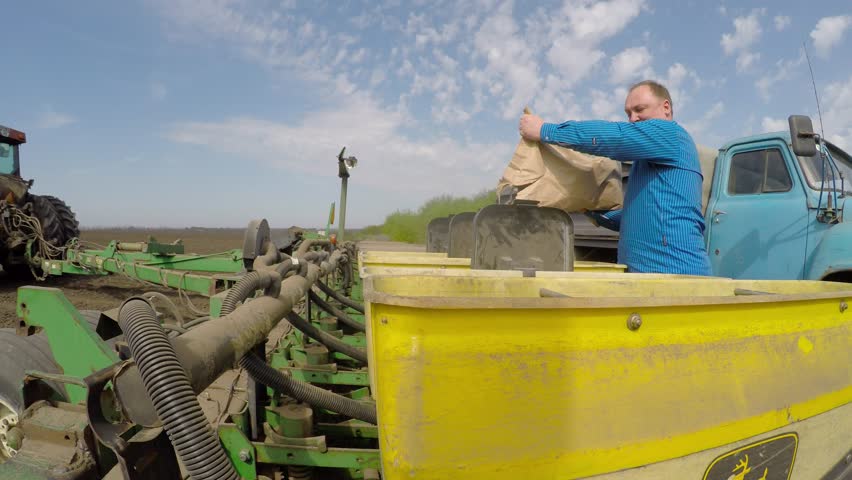 The farmer sleeps grain in a special tractor for planting wheat. Eastern Ukraine. Planting of spring wheat.