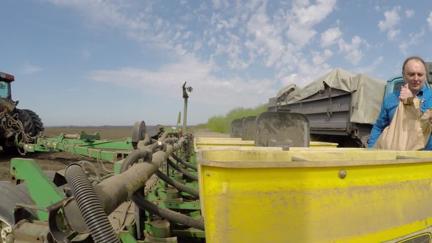 The farmer sleeps grain in a special tractor for planting wheat. Eastern Ukraine. Planting of spring wheat.