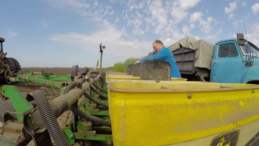The farmer sleeps grain in a special tractor for planting wheat. Eastern Ukraine. Planting of spring wheat.
