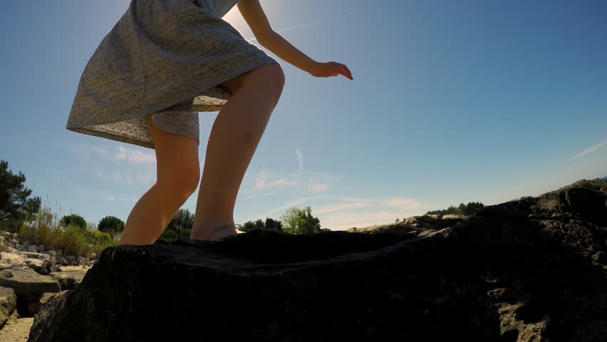 Girl standing on rocks and looking into the sea 