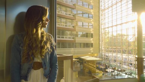 Cinemagraph of woman riding up a glass elevator. Young stylish woman going up glass elevator in modern hotel in Downtown Greenville South Carolina. स्टॉक व्हिडिओ