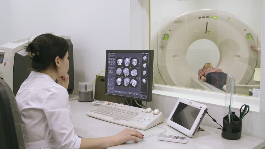 Doctor looking at computer screen while patient moving in mri machine Royalty-Free Stock Footage #16003876