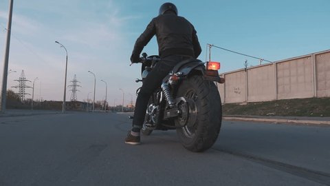 Young man doing a tire burnout on motorcycle on the road at sunset, slow motion, steady come