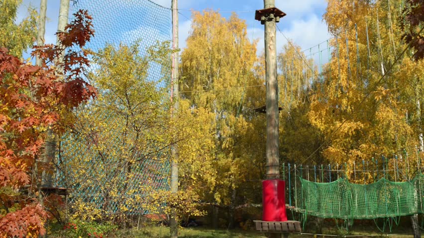Small girl in adventure park. Adventure park is place which can contain wide variety of elements, such as rope climbing exercises, obstacle courses and zip-lines. They intended for recreation.