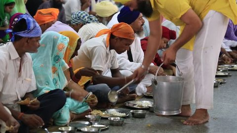 AMRITSAR, INDIA - SEPTEMBER 27, 2014: Unidentified poor indian people eating free food at a soup kitchen in the Sikh Golden Temple