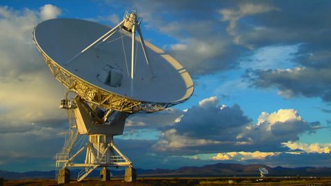 A satellite dish moves in time-lapse against a beautiful sky