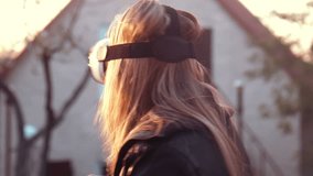 Young woman uses VR helmet with head mount display at home in the yard 