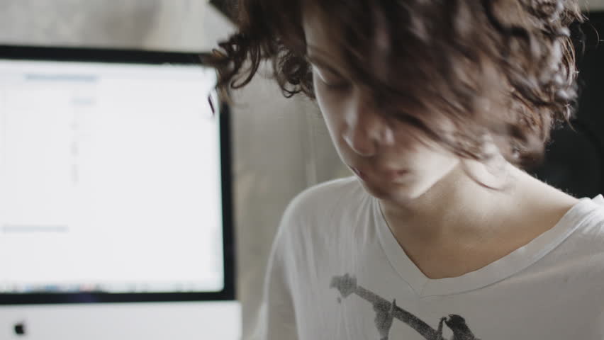 Young Men With Long Hair Practicing Playing An Electric Guitar At Home