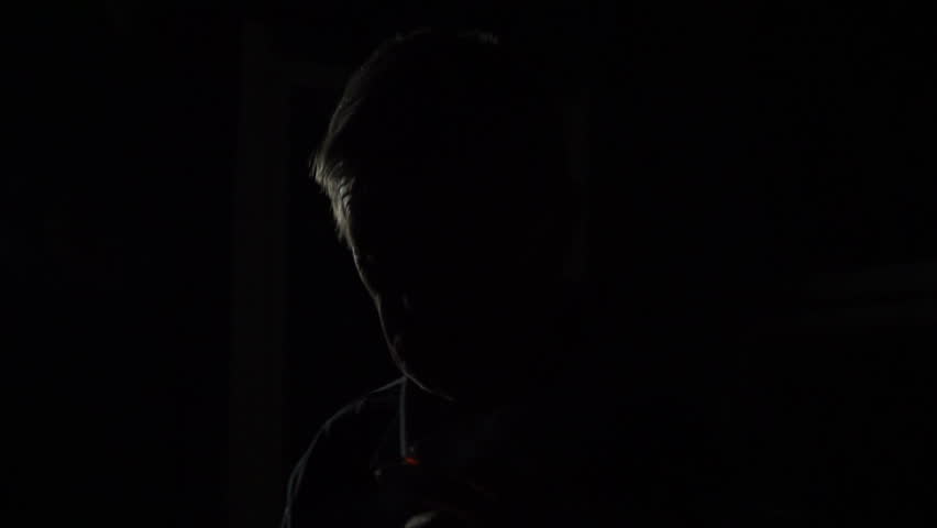 an old man smoking a cigarette at night