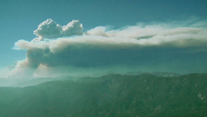 Smoke billows from a mountain wildfire