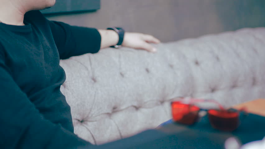 Young businessman using smartwatch sitting in cafe.