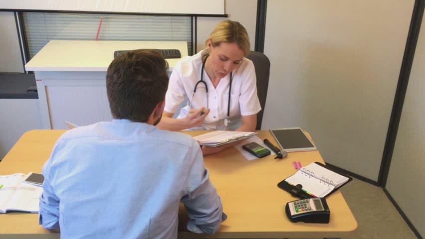 Young attractive woman doctor taking notes while patient speak